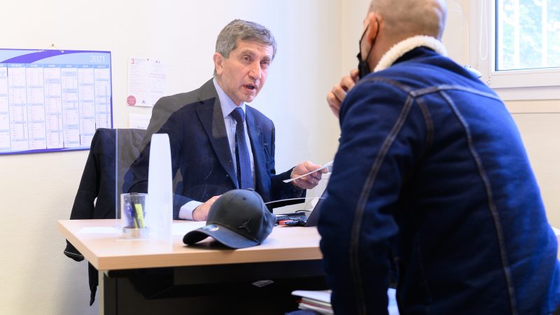 photographie d'une permanence d'un délégué du Défenseur des droits - un homme derrière un bureau discute avec un autre homme venu lui demander conseil